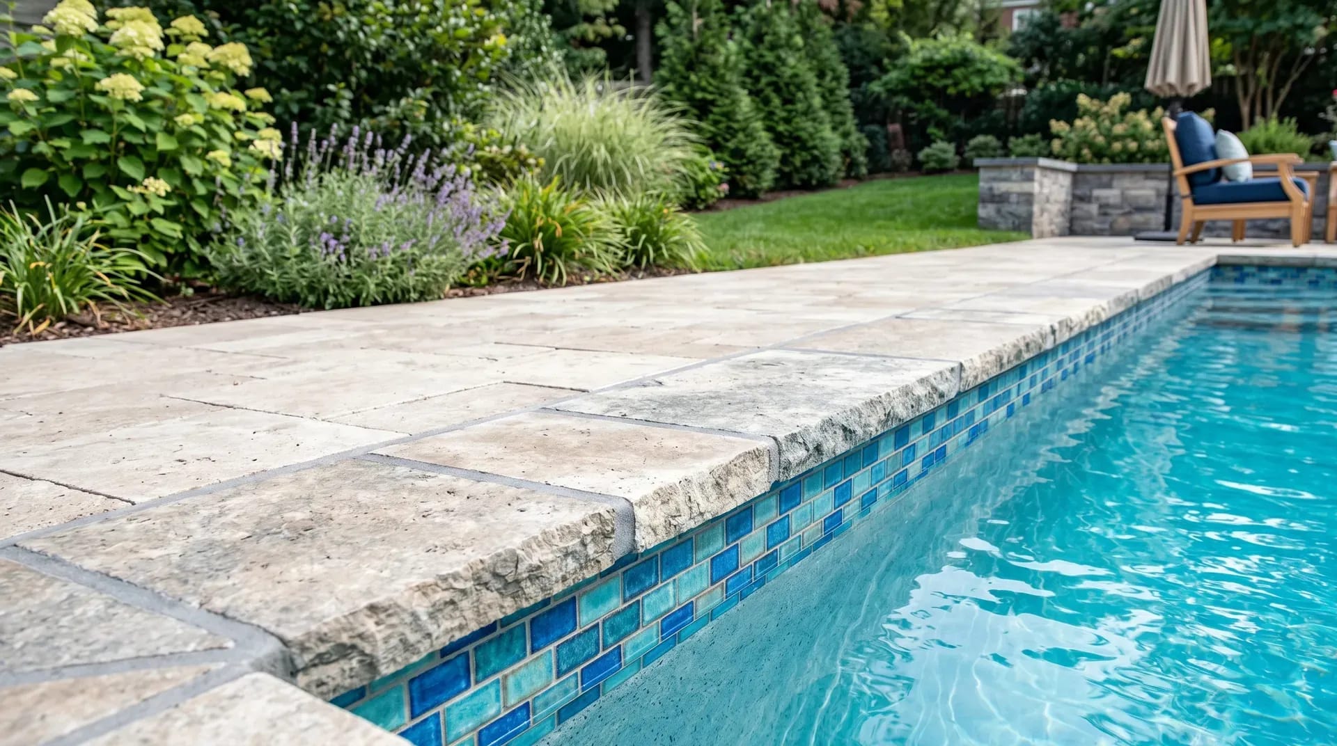 Newly installed natural-stone pool coping with fresh glass-mosaic waterline tile