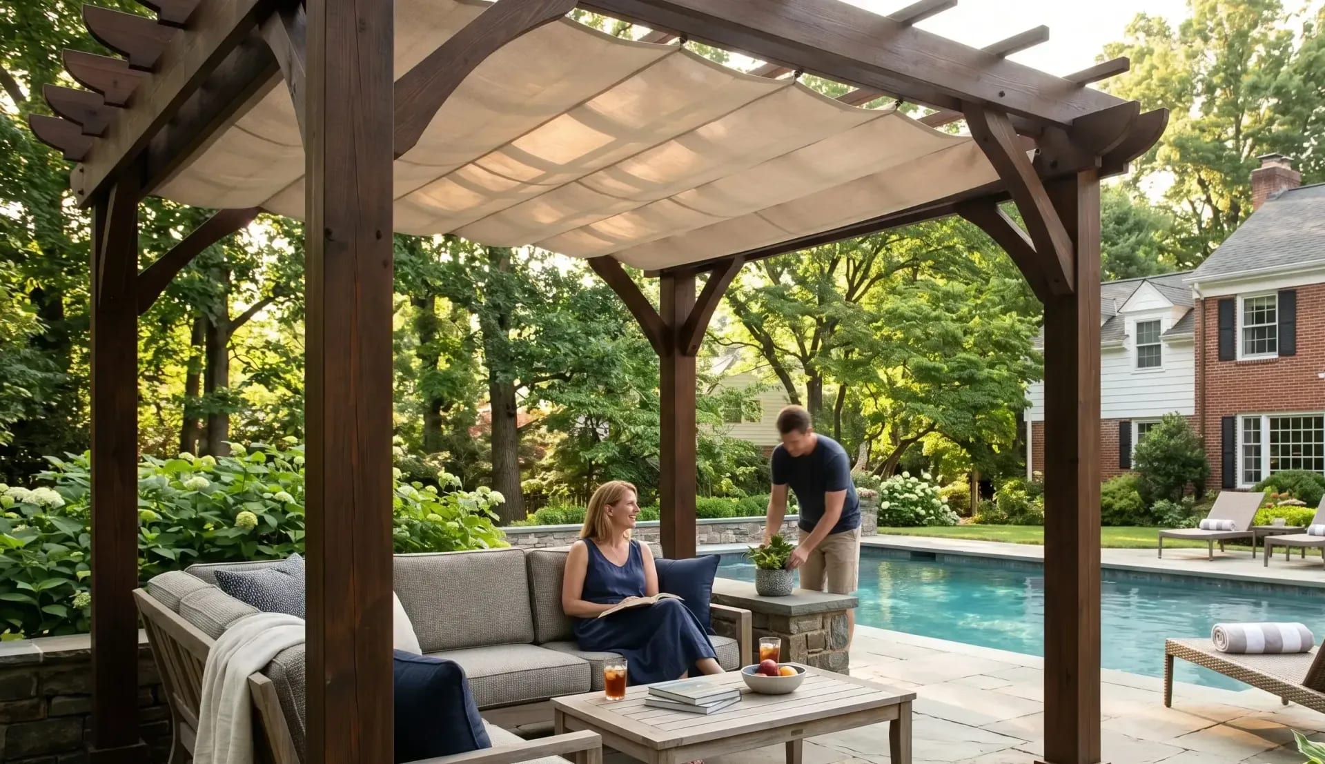 Wooden pergola shading an outdoor lounge area beside an inground pool in a landscaped backyard