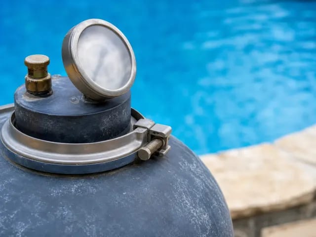 Pool filter tank clamp band, pressure gauge, and air relief valve at a residential equipment pad