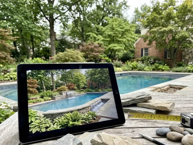 Pool water feature design concept shown with stone samples beside an inground pool
