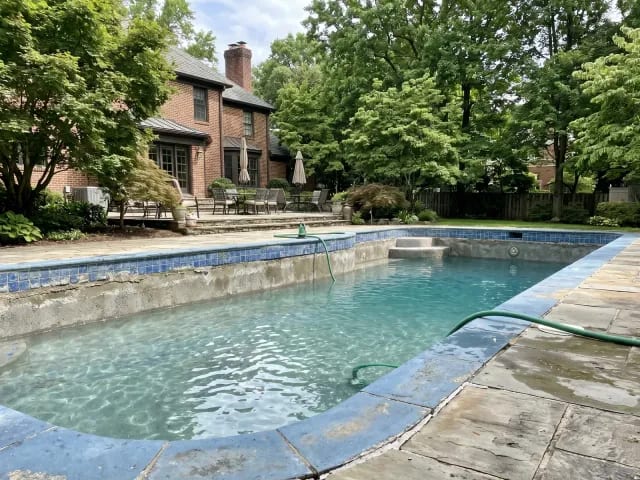 Inground pool partially drained to expose the old waterline tile band